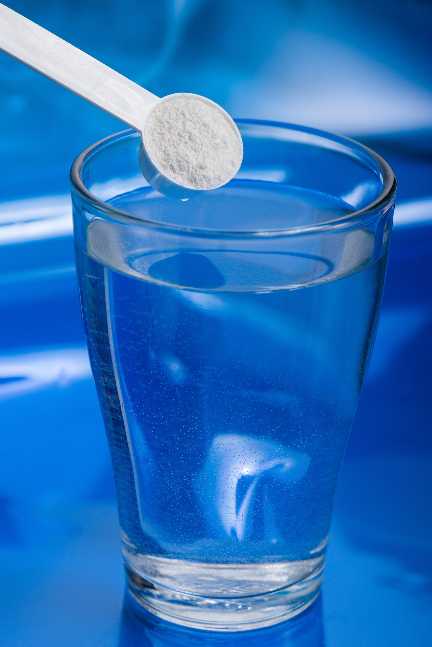 Sport supplement, creatine, hmb, bcaa, amino acid or vitamin - mesure with powder over a glass of water. Sport nutrition concept.